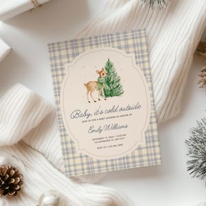 Op de afbeelding: Een rechthoekige uitnodigingskaart voor een babyshower met een lichtblauwe en crèmekleurige ruitjesachtergrond. Het midden heeft een crèmekleurig geschulpt kader met een aquarelillustratie van een reekalf met een groene sjaal bij een dennenboom.