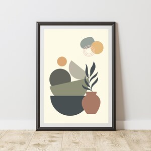 May include: A framed wall art print featuring a cream background with abstract geometric shapes in charcoal, olive, sage, and terracotta. The composition includes stacked semi-circles, circles, and a terracotta vase containing a dark leaf sprig.
