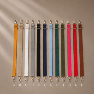 May include: Twelve adjustable bag straps in various colors including yellow, beige, white, gray, black, navy, light blue, dark green, olive, pink, red, and brown. Each strap features gold-tone metal swivel hooks and sliders, labeled A through L.
