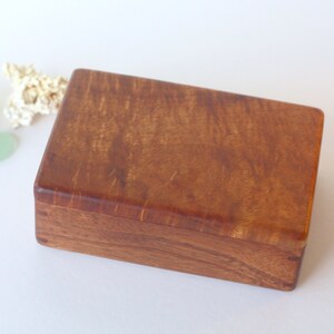 May include: A rectangular wooden box with a rich brown finish. The wood grain is visible and has a natural, rustic look.