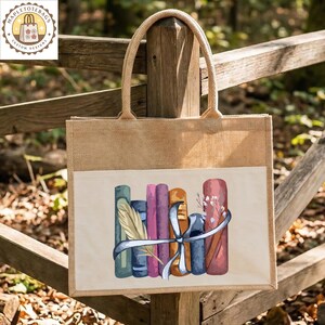 May include: A beige burlap tote bag with a cream-colored pocket featuring a watercolor illustration of a stack of books tied with a blue ribbon. The bag has sturdy handles and a logo in the upper left corner.