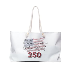 May include: A white tote bag with rope handles featuring a graphic of the American flag and the text "Blessed is the nation whose God is the Lord" followed by the number "250" in large red font with a dark grey shadow effect on the front.