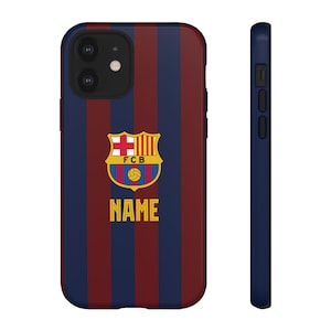 May include: A navy blue and maroon striped phone case with the FCB logo and the word "NAME" in gold. The case has a black side profile.