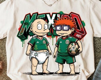 Può includere: Una t-shirt color bianco sporco con la grafica di due personaggi dei cartoni animati che indossano maglie da calcio verdi del Messico. Uno indossa un pannolino, l'altro tiene un pallone da calcio. Dietro, la scritta MEXICO in stile graffiti.