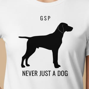 Pode incluir: Camiseta branca com silhueta preta de cachorro, com o texto "GSP" acima do cachorro e "NEVER JUST A DOG" abaixo. A camiseta tem gola redonda.
