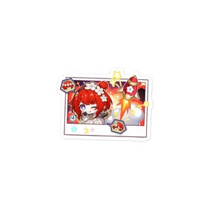 Könnte beinhalten: Ein gestanzter Aufkleber mit einem rechteckigen Rahmen im Polaroid-Stil. Darin zwinkert eine Chibi-Figur mit roten Haaren und einem weißen Blumenkranz. Eine rote Rakete mit einem weißen Blumenemblem startet in eine gelb-orange Explosion.
