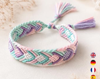 May include: A woven friendship bracelet featuring a chevron pattern in pastel shades of mint green, light pink, lavender, and white. The bracelet is constructed from braided thread and includes two adjustable tie ends finished with small, matching decorative tassels.