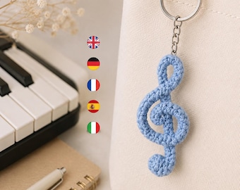 May include: A light blue crochet treble clef keyring attached to a cream-coloured canvas tote bag. The keyring features a silver-toned metal ring and chain, showcasing a textured, yarn-based musical symbol design in a soft, pastel blue shade.
