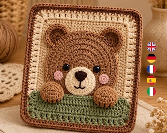Könnte beinhalten: Ein quadratischer Wandbehang aus Häkelarbeit mit einem braunen Bärengesicht, schwarzen Augen, einer dunkelbraunen Nase und rosa Wangen. Der Bär schaut über einen grünen, strukturierten Rand. Das Stück ist von einem cremefarbenen Rand mit dunkelbrauner Kante umgeben.