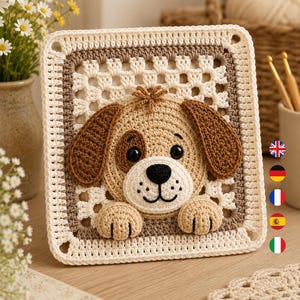 May include: A square crochet granny square featuring a three-dimensional tan and brown puppy face with black eyes and a black nose, with two small paws resting at the bottom edge, framed by a cream and light brown border with a classic openwork pattern.