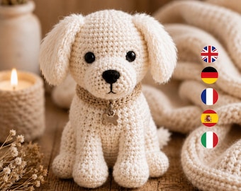 May include: A cream-colored crocheted puppy toy with floppy ears, black plastic eyes, and a black stitched nose. The puppy wears a tan crocheted collar with a small, silver-toned metal bone-shaped charm hanging from the center of the collar.