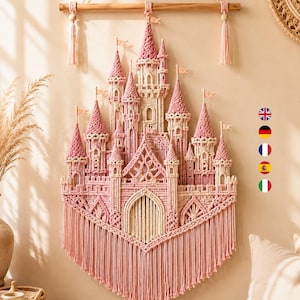 May include: A macrame wall hanging shaped like a castle, crafted from cream and dusty pink cord. The design features multiple towers with pointed roofs, small flags, and a central arched doorway. It hangs from a wooden rod with decorative tassels.