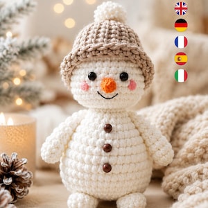 May include: A white crocheted snowman doll featuring a beige textured hat with a pom-pom on top, black bead eyes, a small orange carrot-shaped nose, pink stitched cheeks, and three dark brown circular buttons down the center of its body.