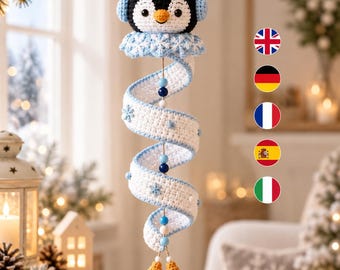 Könnte beinhalten: Ein gehäkelter Hängeschmuck mit einem schwarz-weißen Pinguinkopf und hellblauen Ohrenschützern, befestigt an einem weißen Spiralschwanz, der mit hellblauen Schneeflocken und blauen sowie weißen Holzperlen verziert ist und in zwei gelben Quasten endet.