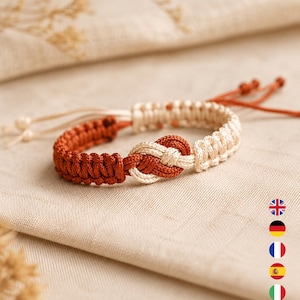 Peut inclure: Un bracelet en macramé avec un nœud central et des sections alternées de cordon couleur rouille et crème. Le bracelet présente des cordons de serrage réglables avec de petits nœuds aux extrémités, affichant une texture tissée sur toute la bande.