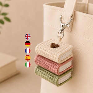 Puede incluir: Un llavero de ganchillo con tres libros en miniatura apilados en color crema, rosa empolvado y verde salvia, unido a un mosquet&oacute;n de metal plateado. El libro superior de color crema tiene un peque&ntilde;o coraz&oacute;n marr&oacute;n bordado.