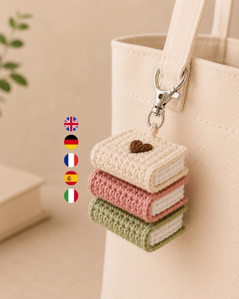 Puede incluir: Un llavero de ganchillo con tres libros en miniatura apilados en color crema, rosa empolvado y verde salvia, unido a un mosquet&oacute;n de metal plateado. El libro superior de color crema tiene un peque&ntilde;o coraz&oacute;n marr&oacute;n bordado.