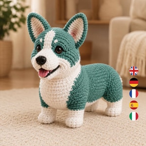 May include: A handcrafted crochet corgi plush toy featuring a teal and white colour scheme. The dog has pointed ears, dark eyes, a black nose, and an open mouth with a pink tongue. The body is textured with yarn stitches and stands on four legs.
