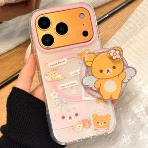 May include: Clear phone case with a pink border and a cartoon bear design. The case features the text "Sweet dreams" and "Take a picture". A matching pop-socket is attached to the phone.