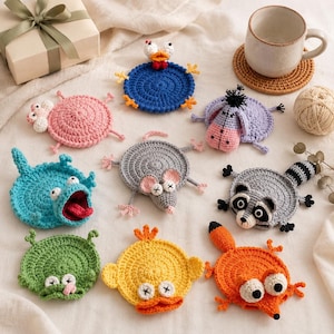 May include: A collection of nine round, crocheted animal coasters featuring various designs including a blue bird, pink pig, purple donkey, blue frog, gray mouse, raccoon, green frog, yellow chick, and orange fox, all with distinct facial features.