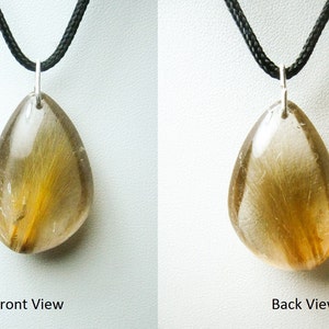 May include: A teardrop-shaped pendant with a clear quartz crystal containing golden rutile inclusions. The pendant is on a black cord.
