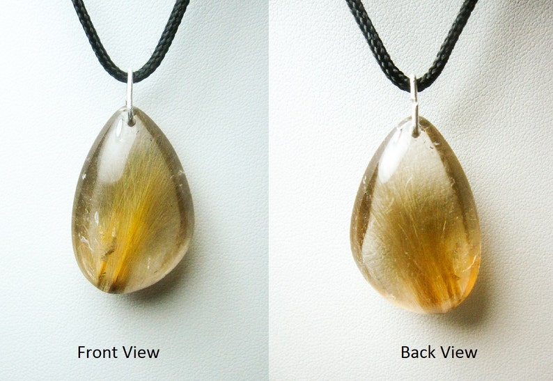 May include: A teardrop-shaped pendant with a clear quartz crystal containing golden rutile inclusions. The pendant is on a black cord.