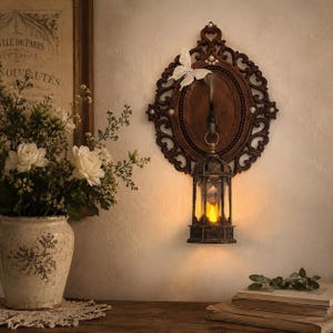 May include: Ornate, dark brown wall sconce with a decorative frame, a butterfly accent, and a hanging lantern. The lantern has a warm, yellow light. A vase of white flowers sits on a wooden surface.