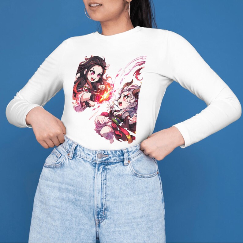 May include: White long-sleeve shirt featuring two anime-style characters with fiery effects. The characters have dark hair and are set against a white background. The shirt is paired with light blue denim jeans.