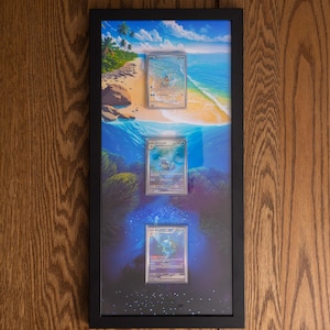 May include: A black rectangular frame containing three vertically aligned trading cards. The background features a continuous tropical beach scene transitioning from a sandy shore at the top to a deep blue underwater coral reef at the bottom.