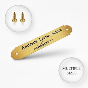 May include: A gold-colored nameplate with the text "Andrada Larisa Achim" and a signature. Two gold screws are in a circle above the nameplate. A white circle with "MULTIPLE SIZES" is in the lower right corner.