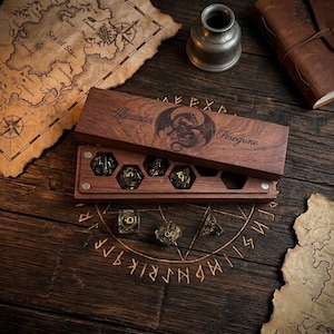 May include: A rectangular wooden box with a sliding lid engraved with a dragon and the text Alexander Peregrine. The box contains hexagonal slots holding several multi-faceted dice with gold numbers. Three additional dice rest outside.