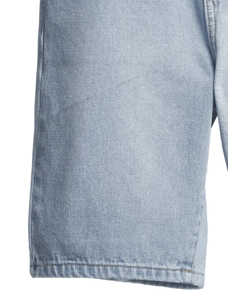 May include: Close-up of light blue denim shorts. The shorts have a classic design with visible stitching and a textured fabric. The denim appears to be pre-washed, giving it a faded appearance. The image focuses on the fabric and construction details.