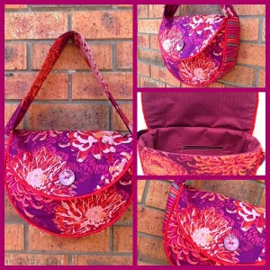 May include: A handmade shoulder bag with a vibrant floral pattern in shades of purple, pink, and orange. The bag features a curved shape, a button closure, and a red trim. The interior is a solid purple fabric. The strap is a matching floral print.