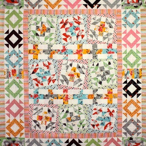 May include: A colorful quilt with a patchwork design featuring various geometric shapes and floral patterns. The quilt is made up of squares, triangles, and diamonds in shades of pink, blue, green, yellow, and white.
