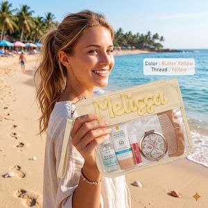 May include: A butter yellow zippered pouch with a clear front panel featuring the name Melissa in yellow thread. The pouch contains a bottle of sea salt hair spray, a tube of SPF 50 sunscreen, a lip balm, a round compact mirror, and a wooden comb.