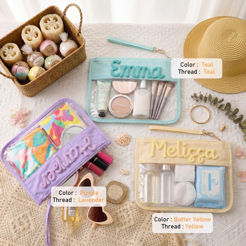 May include: Three rectangular clear cosmetic pouches with wrist straps, featuring embroidered names. One teal pouch labeled Emma, one purple pouch labeled Harper, and one butter yellow pouch labeled Melissa. Each contains various personal care items.