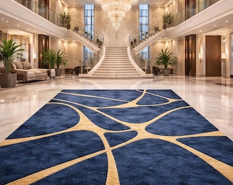 Puede incluir: Una alfombra azul rectangular grande con un diseño abstracto dorado. La alfombra está colocada en un gran salón con suelo de mármol, una gran lámpara de araña y una escalera. Las dimensiones de la alfombra son de aproximadamente 3 metros por 4,5 metros.