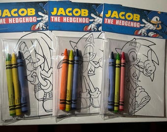May include: Three clear plastic packets each containing a coloring page and crayons. Each packet has a blue header with the text "JACOB THE HEDGEHOG" and a cartoon image of Sonic the Hedgehog. The coloring pages feature line art of Sonic.