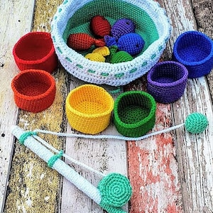 Könnte beinhalten: Ein handgefertigtes Häkel-Angelspiel-Set. Das Set enthält einen weiß-blauen Korb mit bunten Häkelfischen und mehrere kleine, runde Häkelschalen in verschiedenen Farben. Eine Häkelangel ist ebenfalls enthalten.