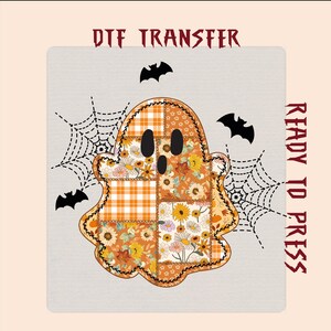 May include: A DTF transfer sheet featuring a central ghost graphic composed of orange, yellow, and white patchwork patterns including sunflowers, leaves, and plaid. The design includes black spiderwebs and bats, with the text DTF TRANSFER READY TO PRESS.