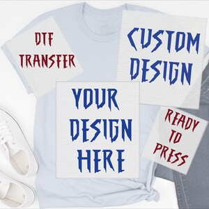 May include: A light blue t-shirt with white sneakers and denim jeans. The shirt has four white squares with text: "DTF TRANSFER", "CUSTOM DESIGN", "YOUR DESIGN HERE", and "READY TO PRESS" in red and blue.