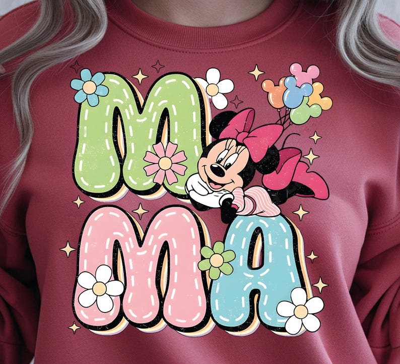 Puede incluir: Sudadera burdeos con la palabra "MAMA" en letras de burbujas. Las letras son verdes, rosas y azules, decoradas con flores y estrellas. Minnie Mouse aparece con un lazo rosa y globos.