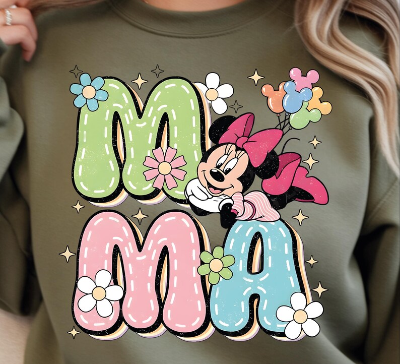 Puede incluir: Sudadera verde oliva con la palabra "MAMA" en letras grandes y coloridas. La "M" es verde, la "A" es azul y las otras "M" y "A" son rosas. Minnie Mouse aparece en el dise&ntilde;o, sosteniendo globos y rodeada de flores y estrellas.