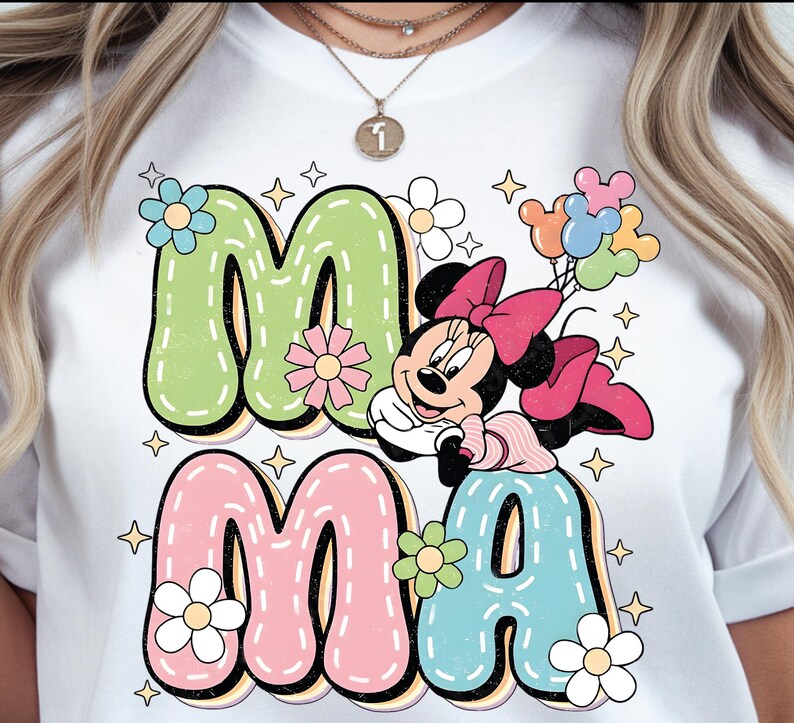 Puede incluir: Camiseta blanca con las palabras "MA MA" en letras coloridas. La "M" es verde, la "A" es rosa y la segunda "A" es azul. Minnie Mouse aparece con un lazo rosa y globos.