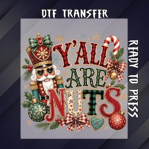 May include: A DTF transfer ready to press featuring a nutcracker wearing heart-shaped sunglasses, surrounded by Christmas ornaments, holly, and a candy cane. The text reads Y'ALL ARE NUTS in red, green, and plaid patterns against a gray background.