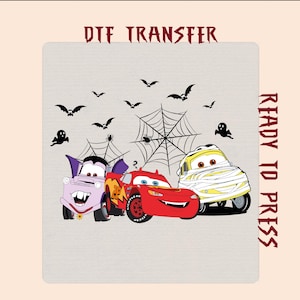 May include: A DTF TRANSFER READY TO PRESS graphic featuring three cartoon cars dressed for Halloween: a purple vampire car, a red race car, and a yellow mummy car, surrounded by black spiderwebs, spiders, bats, and ghosts on a light background.
