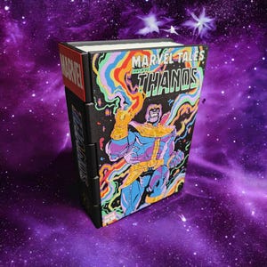 May include: A Marvel Tales comic book featuring Thanos on the cover with a psychedelic, multi-coloured smoke effect. The book has a black spine with the word Marvel in red and Thanos in blue. The cover art displays Thanos in his gold and blue armour.