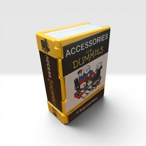 Puede incluir: Un pequeño objeto decorativo rectangular de color amarillo y blanco con forma de libro titulado Accessories for Dummies. La portada presenta una ilustración gráfica de dos personajes de dibujos animados y varios objetos pequeños, con el texto T. Organized Mind.
