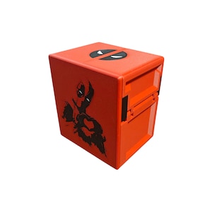 May include: A bright orange, cube-shaped storage box featuring a black Deadpool graphic on one side and the Deadpool logo on top. The box has a hinged lid and a latch closure. The overall design is a bold and eye-catching.