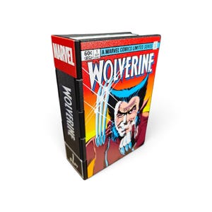 Peut inclure: Une boîte de rangement rectangulaire conçue pour ressembler à une bande dessinée vintage Wolverine. La face avant présente la couverture de la BD avec le titre, tandis que la tranche noire affiche le mot Wolverine et le logo Marvel en rouge.